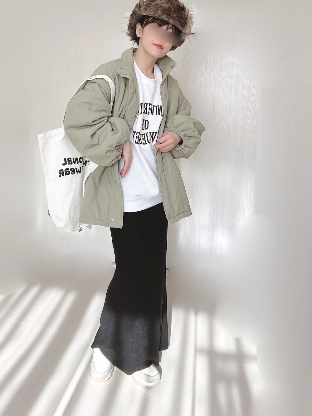 ホワイト系のスウェット、グリーン系のダウンジャケット/コート、ブラック系のスカートを着用したレディースの冬コーディネートの3枚目の写真