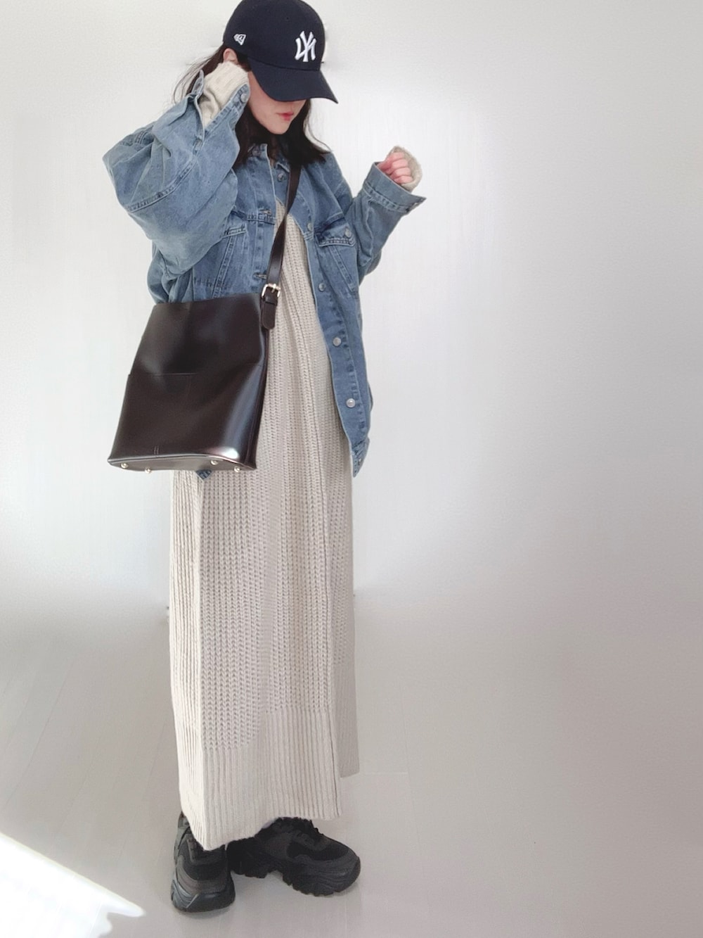ブルー系のデニムジャケット、ホワイト系のワンピース、ブラック系のスニーカーを着用したレディースの冬コーディネートの5枚目の写真