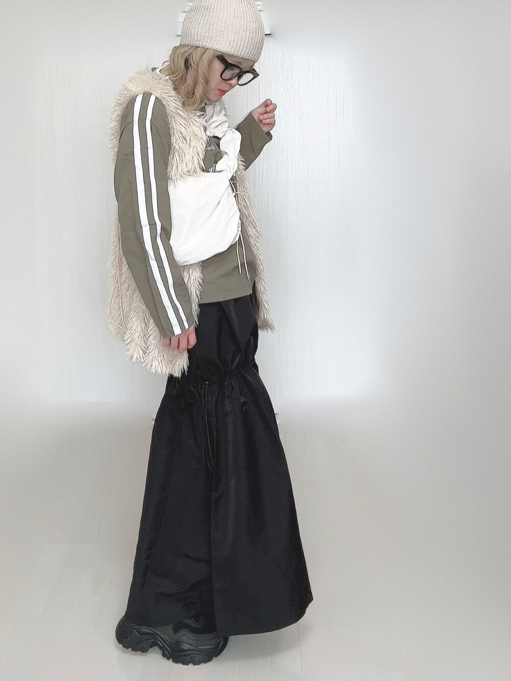 ホワイト系のショルダーバッグ、ホワイト系のベスト、ブラック系のスカートを着用したレディースの春コーディネートの5枚目の写真