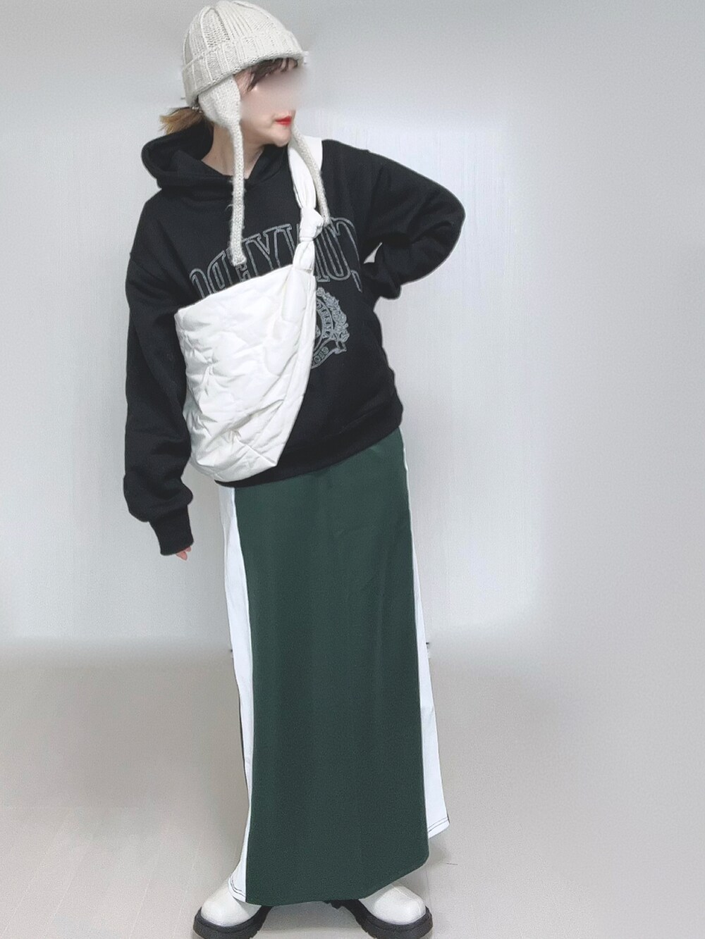 ブラック系のパーカー、ホワイト系のショルダーバッグ、グリーン系のスカートを着用したレディースの冬コーディネートの5枚目の写真