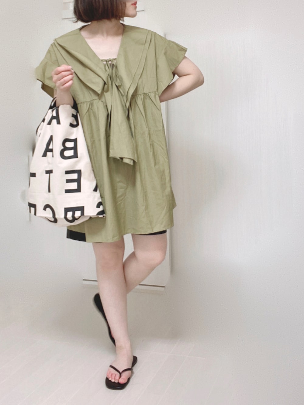 グリーン系のチュニック、ブラック系のその他パンツ、ホワイト系のトートバッグを着用したレディースの夏コーディネートの2枚目の写真