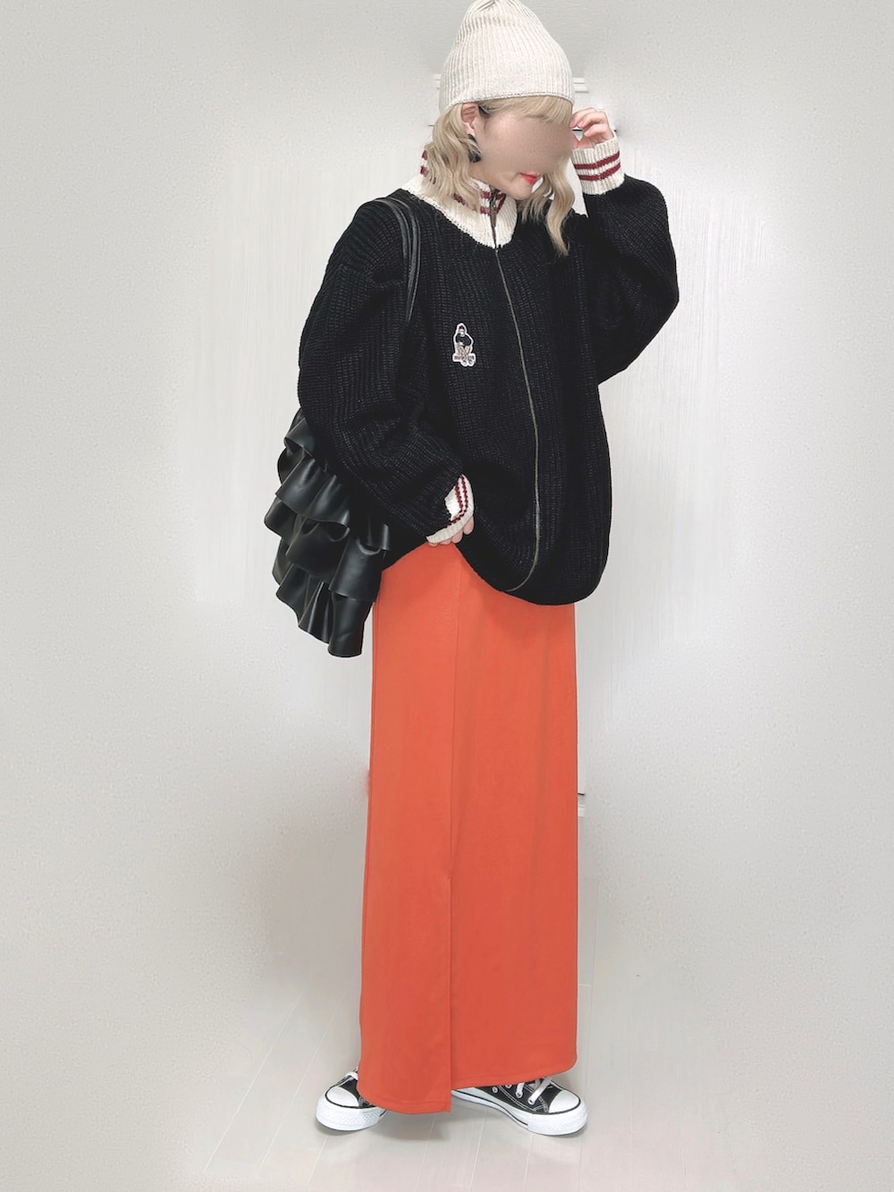 ブラック系のニット/セーター、オレンジ系のスカート、ブラック系のスニーカーを着用したレディースの秋コーディネートの4枚目の写真
