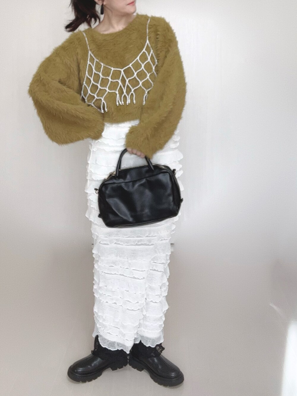 グリーン系のニット/セーター、ホワイト系のベスト、ブラック系のボストンバッグを着用したレディースの冬コーディネートの4枚目の写真