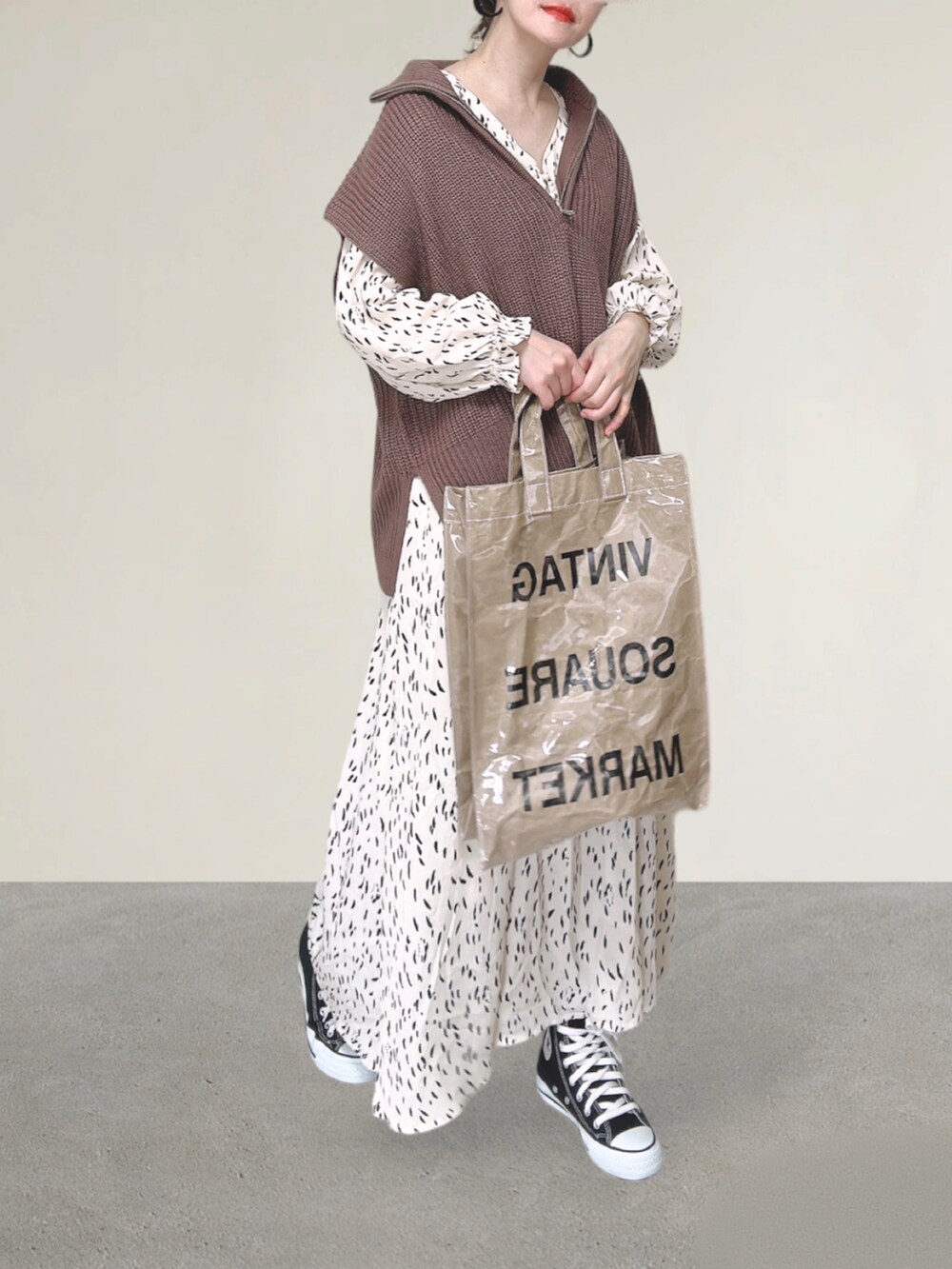 ブラウン系のベスト、ホワイト系のワンピース、グリーン系のトートバッグを着用したレディースの秋コーディネートの2枚目の写真