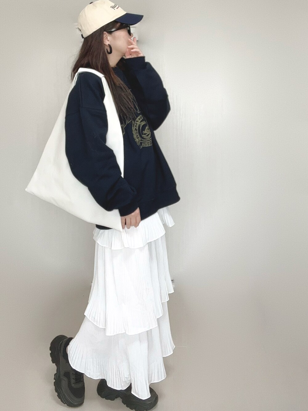 ブルー系のスウェット、ホワイト系のスカート、ホワイト系のショルダーバッグを着用したレディースの秋コーディネートの3枚目の写真