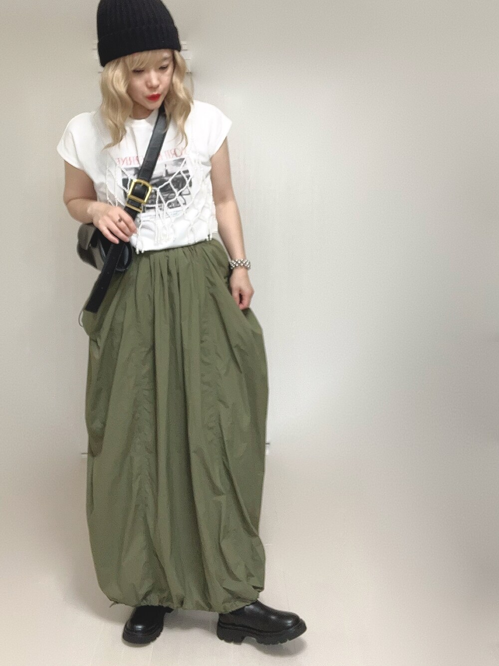 ブラック系のブーツ、グリーン系のスカート、ホワイト系のベストを着用したレディースの秋コーディネートの5枚目の写真