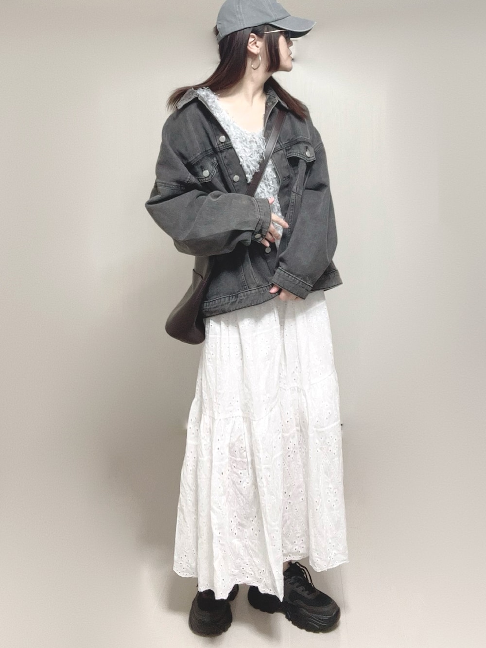 グレー系のベスト、ブラック系のデニムジャケット、ホワイト系のスカートを着用したレディースの春コーディネートの4枚目の写真