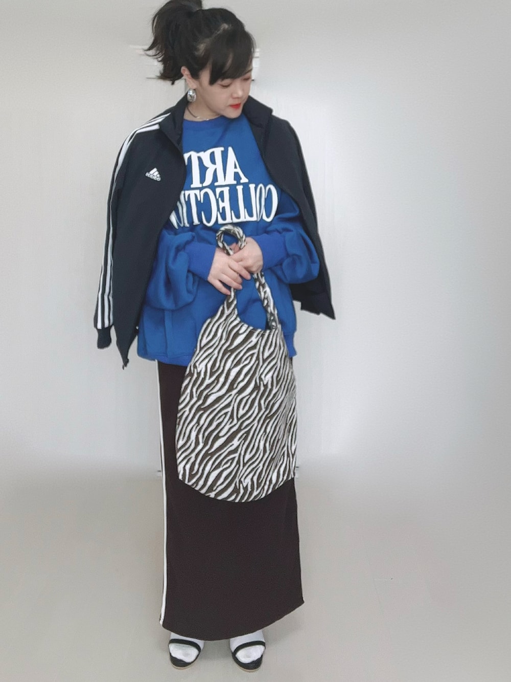 ホワイト系のショルダーバッグ、ブルー系のベスト、ブラック系のサンダルを着用したレディースの冬コーディネートの4枚目の写真