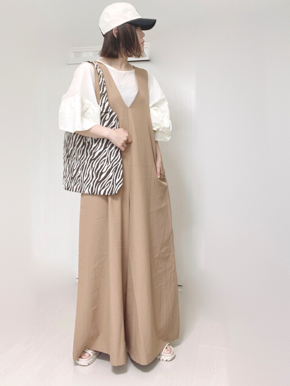 ベージュ系のサロペット/オーバーオール、ホワイト系のシャツ/ブラウス、ホワイト系のサンダルを着用したレディースの夏コーディネートの2枚目の写真