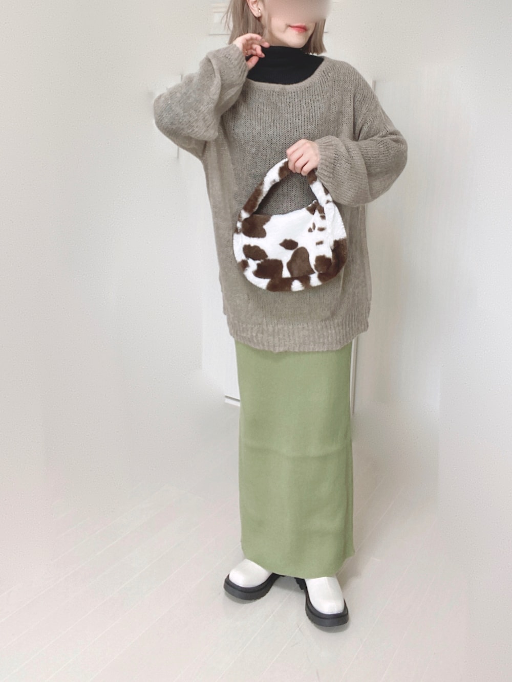 グリーン系のスカート、ベージュ系のニット/セーター、ホワイト系のブーツを着用したレディースの秋コーディネートの5枚目の写真