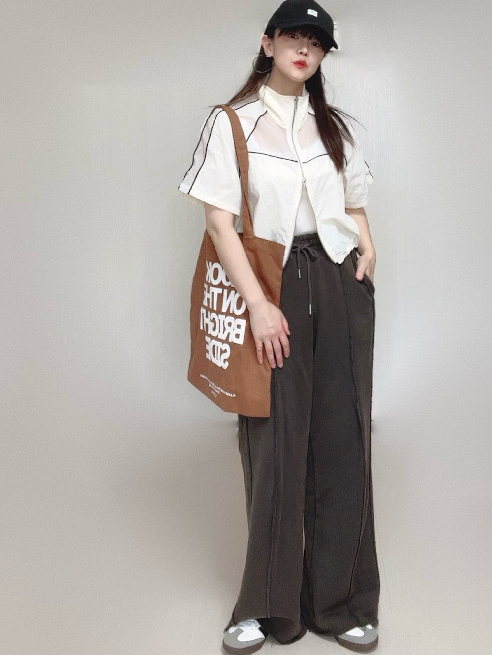 ブラック系のスウェットパンツ、ホワイト系のキャミソール、ホワイト系のブルゾンを着用したレディースの春コーディネートの2枚目の写真