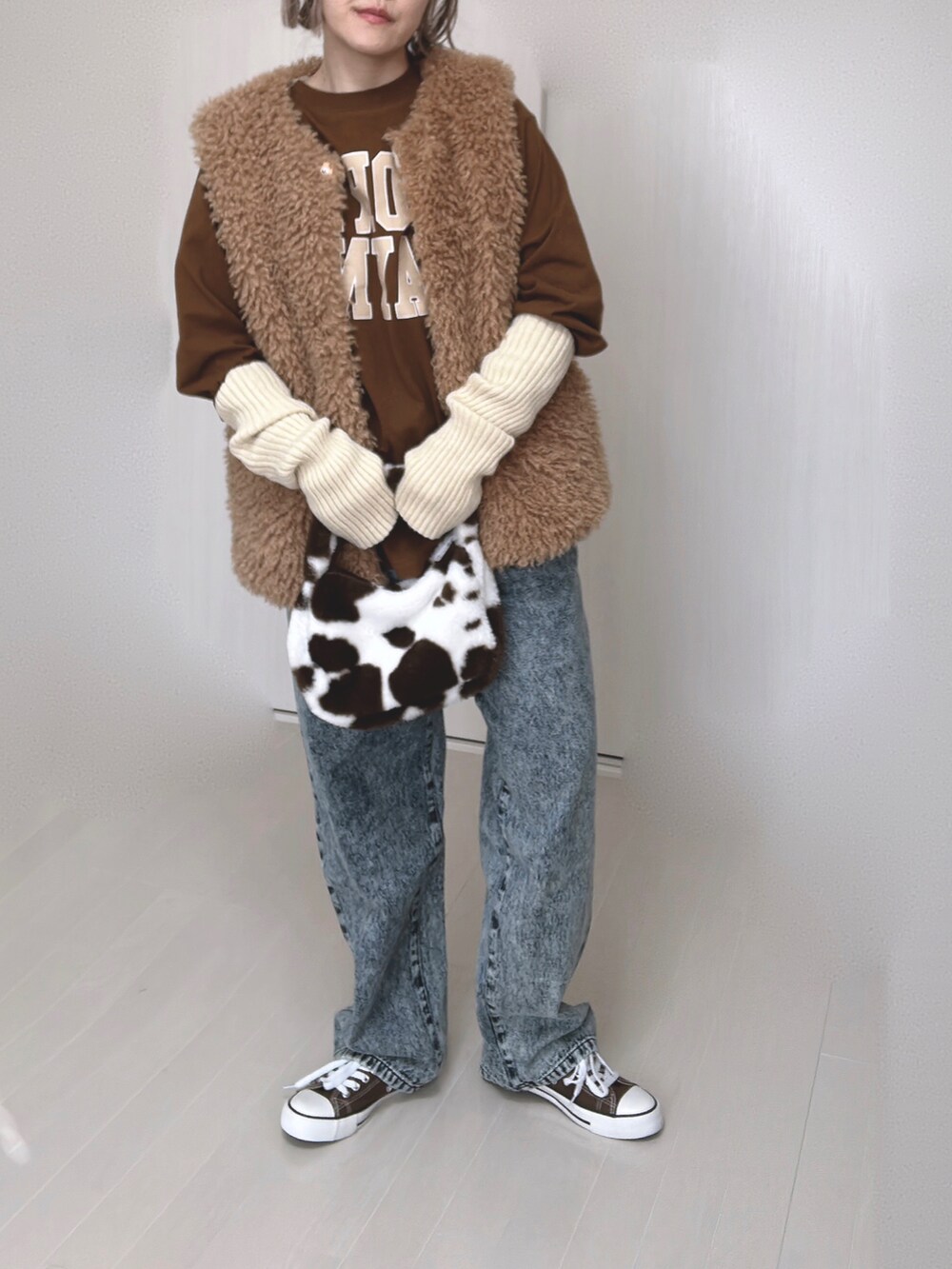 イエロー系のベスト、ブラウン系のTシャツ/カットソー、ブルー系のデニムパンツを着用したレディースの春コーディネートの4枚目の写真