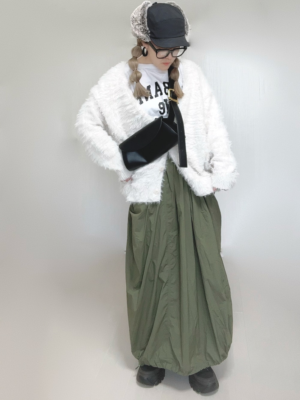 ホワイト系のカーディガン/ボレロ、ホワイト系のTシャツ/カットソー、グリーン系のスカートを着用したレディースの秋コーディネートの4枚目の写真