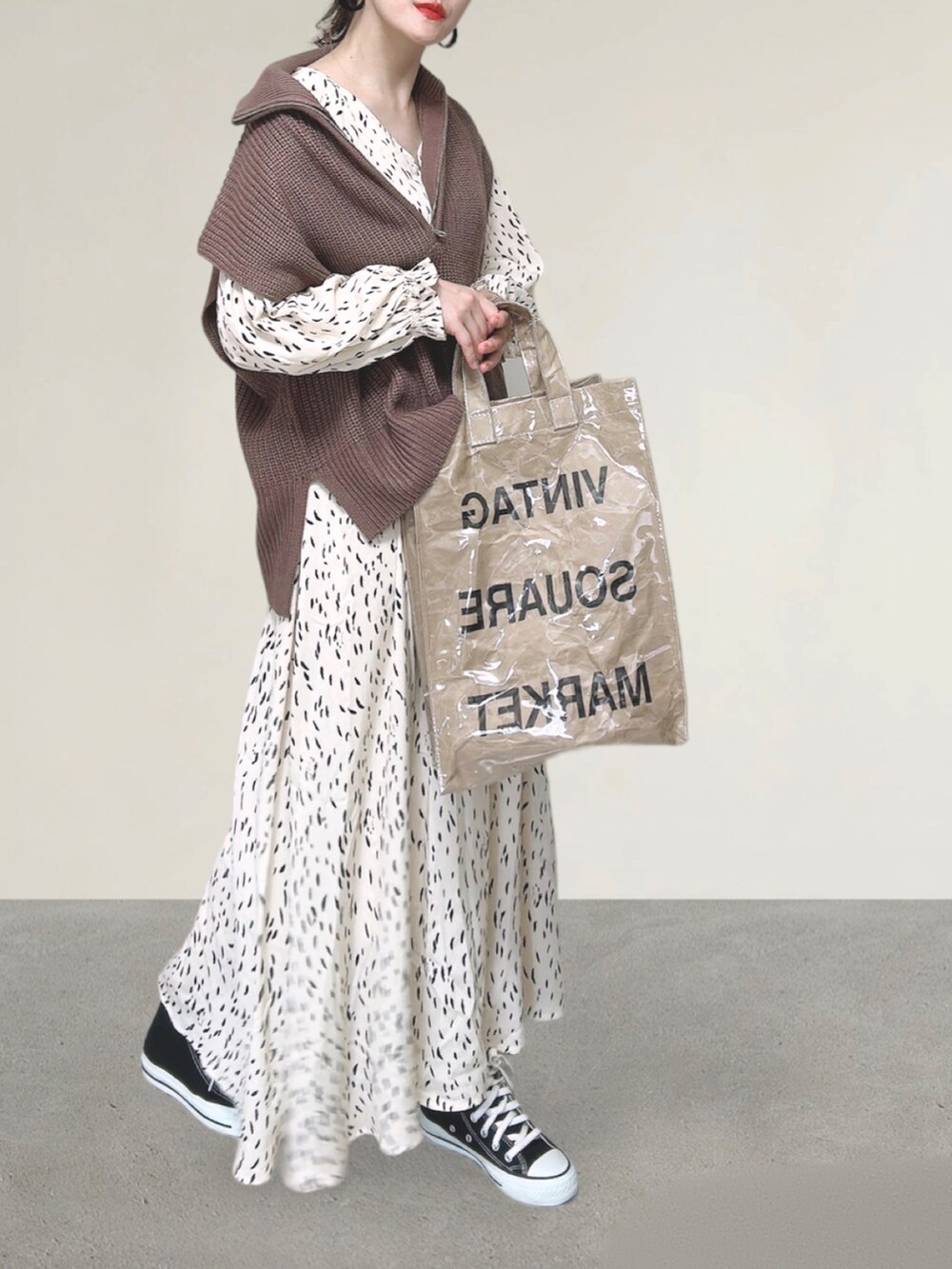 ブラウン系のベスト、ホワイト系のワンピース、グリーン系のトートバッグを着用したレディースの秋コーディネートの3枚目の写真