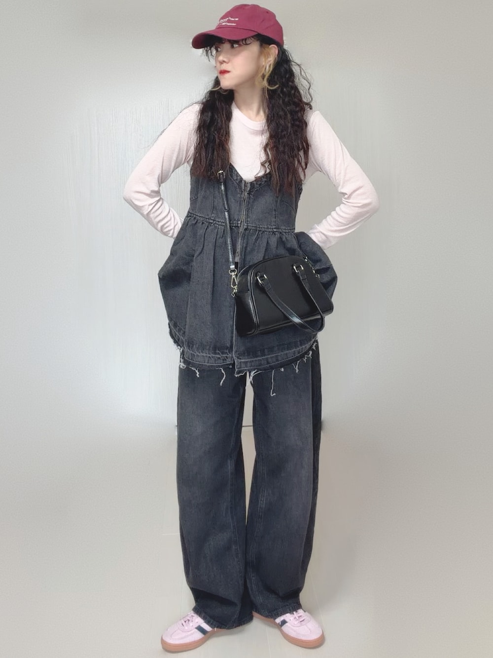 ブラック系のデニムパンツ、ブラック系のボストンバッグ、ピンク系のスニーカーを着用したレディースの春コーディネートの2枚目の写真