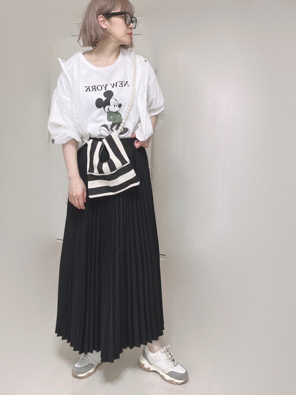 ホワイト系のTシャツ/カットソー、ホワイト系のショルダーバッグ、ブラック系のスカートを着用したレディースの春コーディネートの3枚目の写真