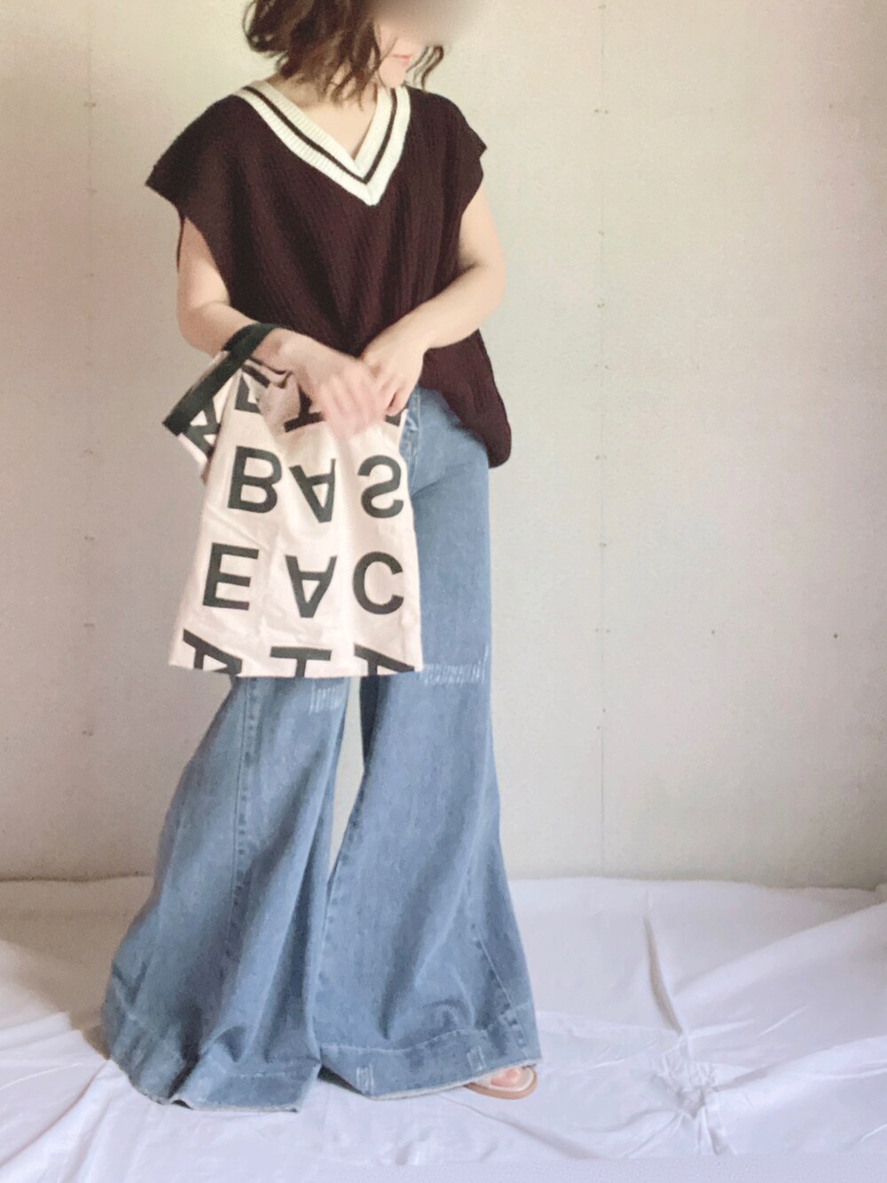 ブラック系のベスト、ホワイト系のトートバッグ、ホワイト系のサンダルを着用したレディースの夏コーディネートの2枚目の写真