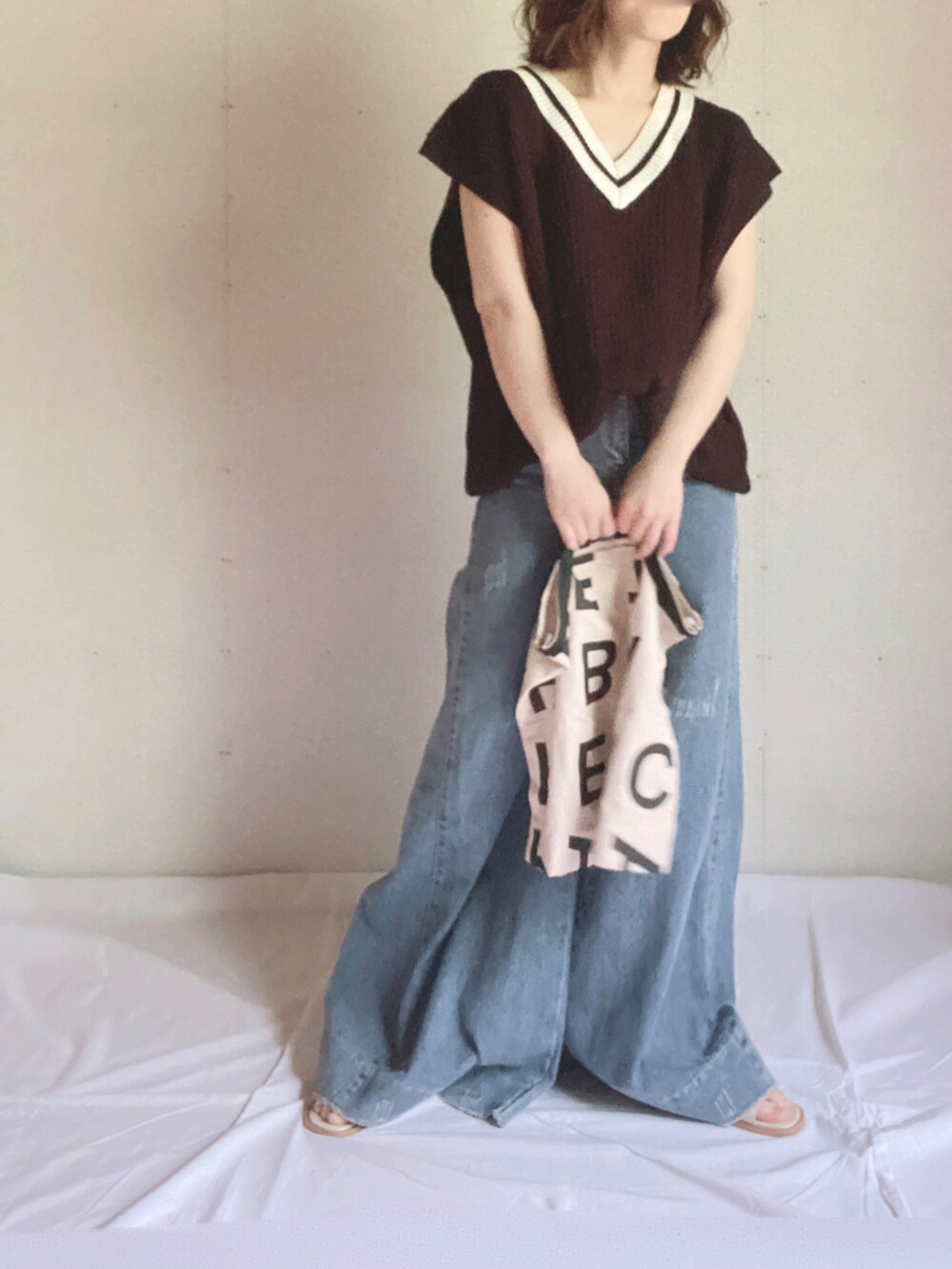 ブラック系のベスト、ホワイト系のトートバッグ、ホワイト系のサンダルを着用したレディースの夏コーディネートの3枚目の写真