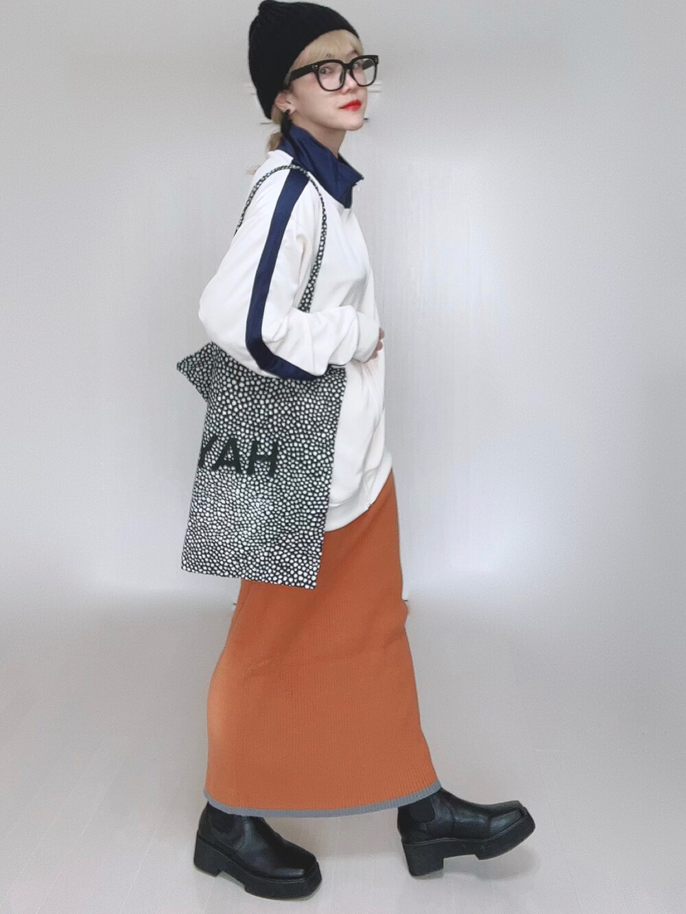 ベージュ系のジャージ、オレンジ系のスカート、ブラック系のブーツを着用したレディースの冬コーディネートの3枚目の写真