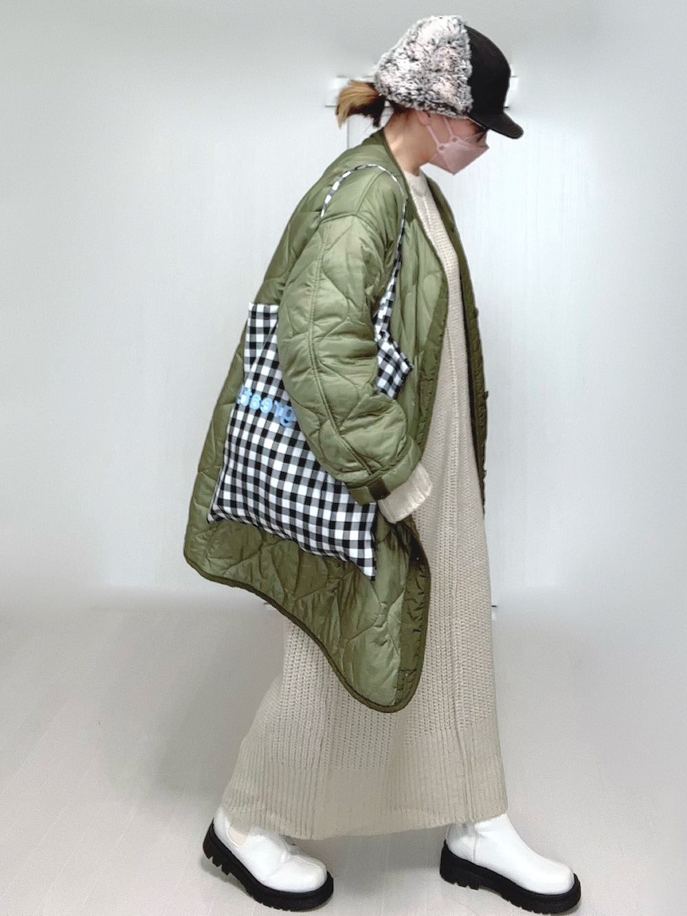 ホワイト系のワンピース、グリーン系のミリタリージャケット、ホワイト系のブーツを着用したレディースの冬コーディネートの3枚目の写真