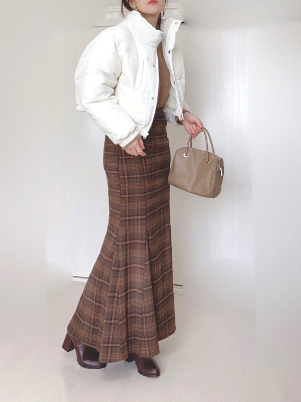 ホワイト系のダウンジャケット/コート、ブラウン系のニット/セーター、ブラウン系のスカートを着用したレディースの秋コーディネートの2枚目の写真