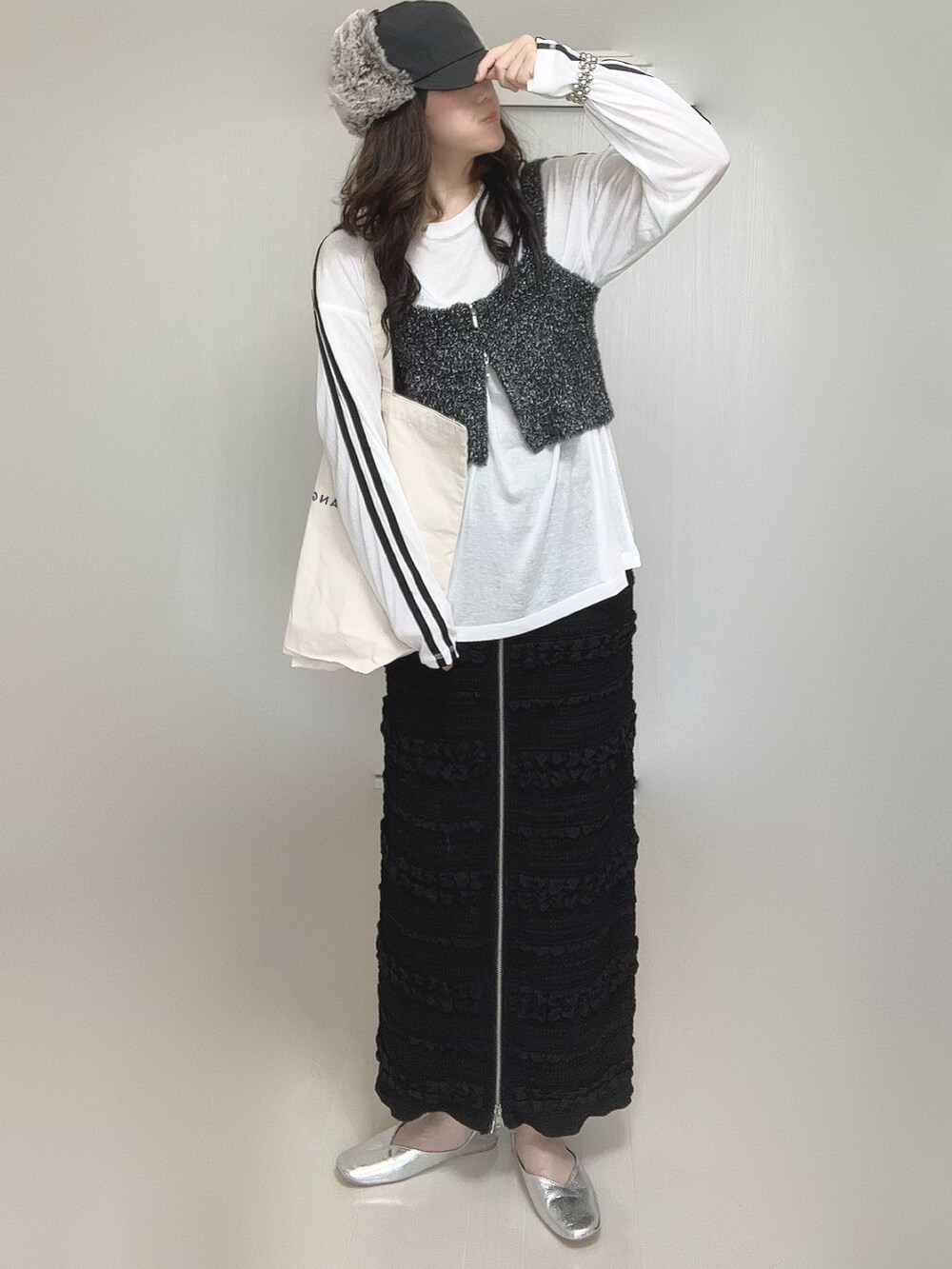 ホワイト系のTシャツ/カットソー、ブラック系のベスト、ブラック系のスカートを着用したレディースの秋コーディネートの5枚目の写真