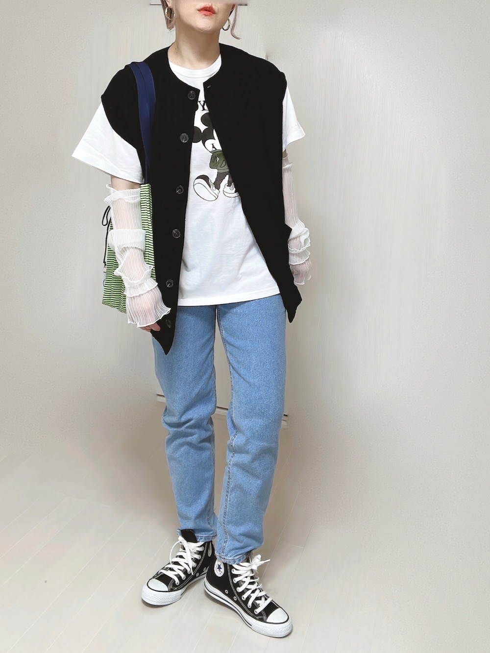 ブルー系のデニムパンツ、ブラック系のベスト、ホワイト系のTシャツ/カットソーを着用したレディースの春コーディネートの3枚目の写真