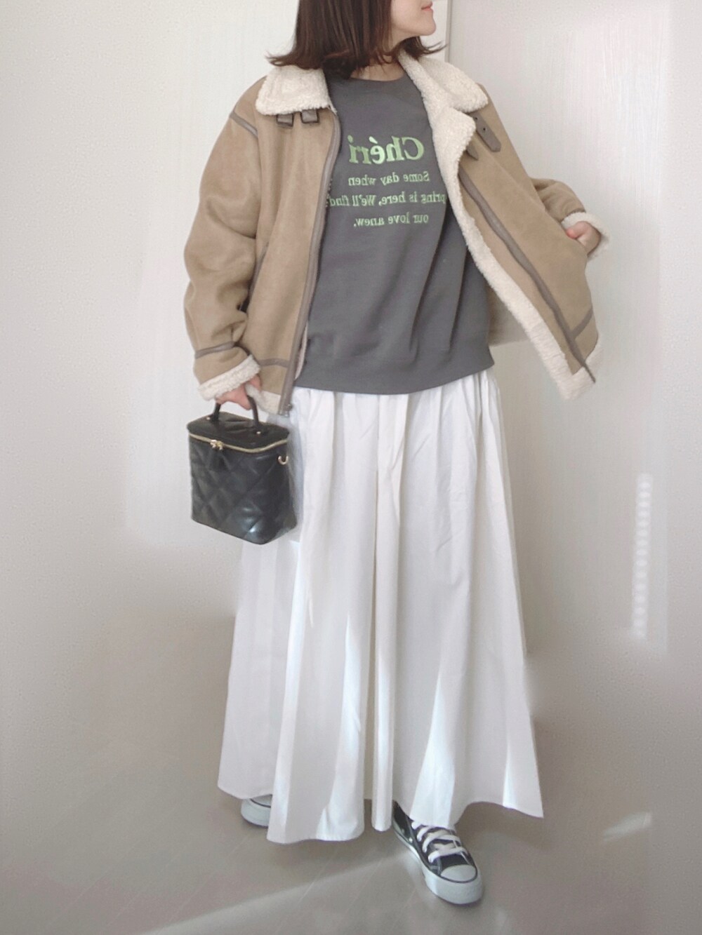 グレー系のスウェット、ホワイト系のスカート、ベージュ系のムートンコートを着用したレディースの冬コーディネートの3枚目の写真