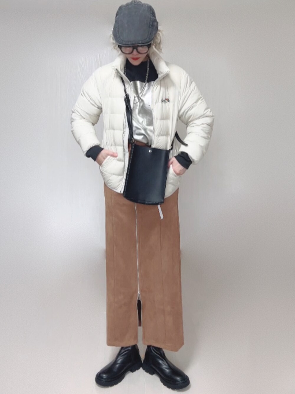 ブラック系のブーツ、ホワイト系のダウンジャケット/コート、ブラック系のショルダーバッグを着用したレディースの秋コーディネートの5枚目の写真