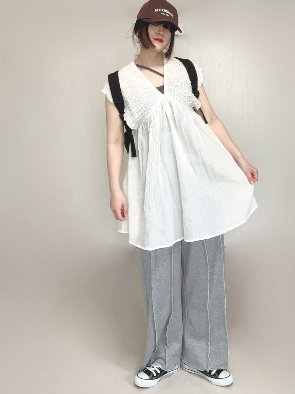 ホワイト系のワンピース、ブラック系のバックパック/リュック、グレー系のスウェットパンツを着用したレディースの春コーディネートの3枚目の写真