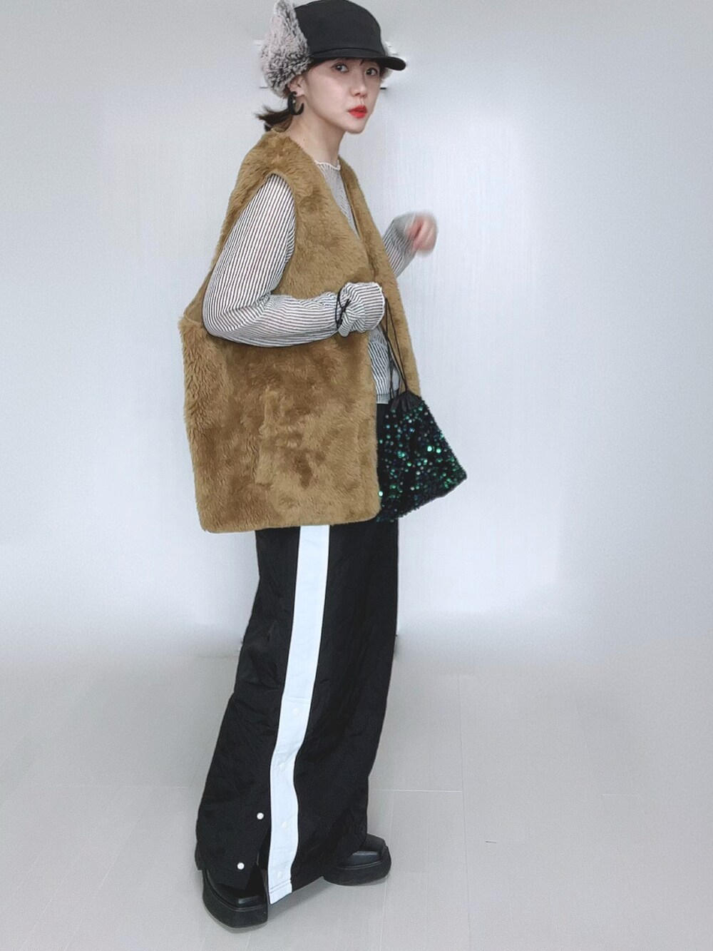 イエロー系のベスト、ホワイト系のシャツ/ブラウス、ブラック系のスカートを着用したレディースの冬コーディネートの2枚目の写真