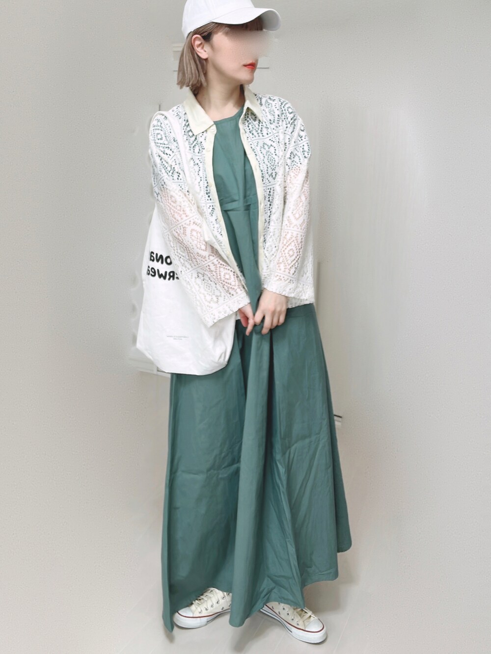 グリーン系のワンピース、ホワイト系のトートバッグ、ホワイト系のスニーカーを着用したレディースの春コーディネートの3枚目の写真