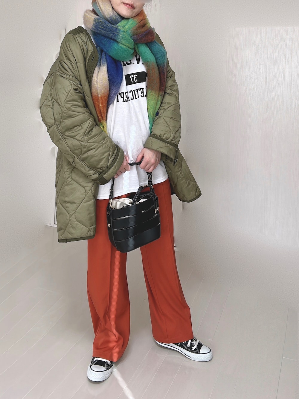 ホワイト系のTシャツ/カットソー、オレンジ系のスラックス、グリーン系のミリタリージャケットを着用したレディースの冬コーディネートの2枚目の写真
