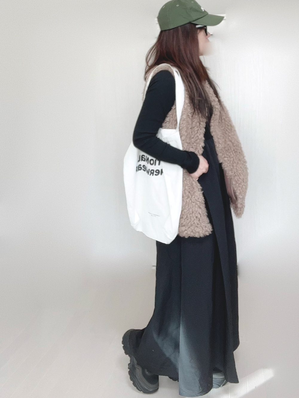 グレー系のワンピース、ベージュ系のベスト、ホワイト系のトートバッグを着用したレディースの冬コーディネートの4枚目の写真