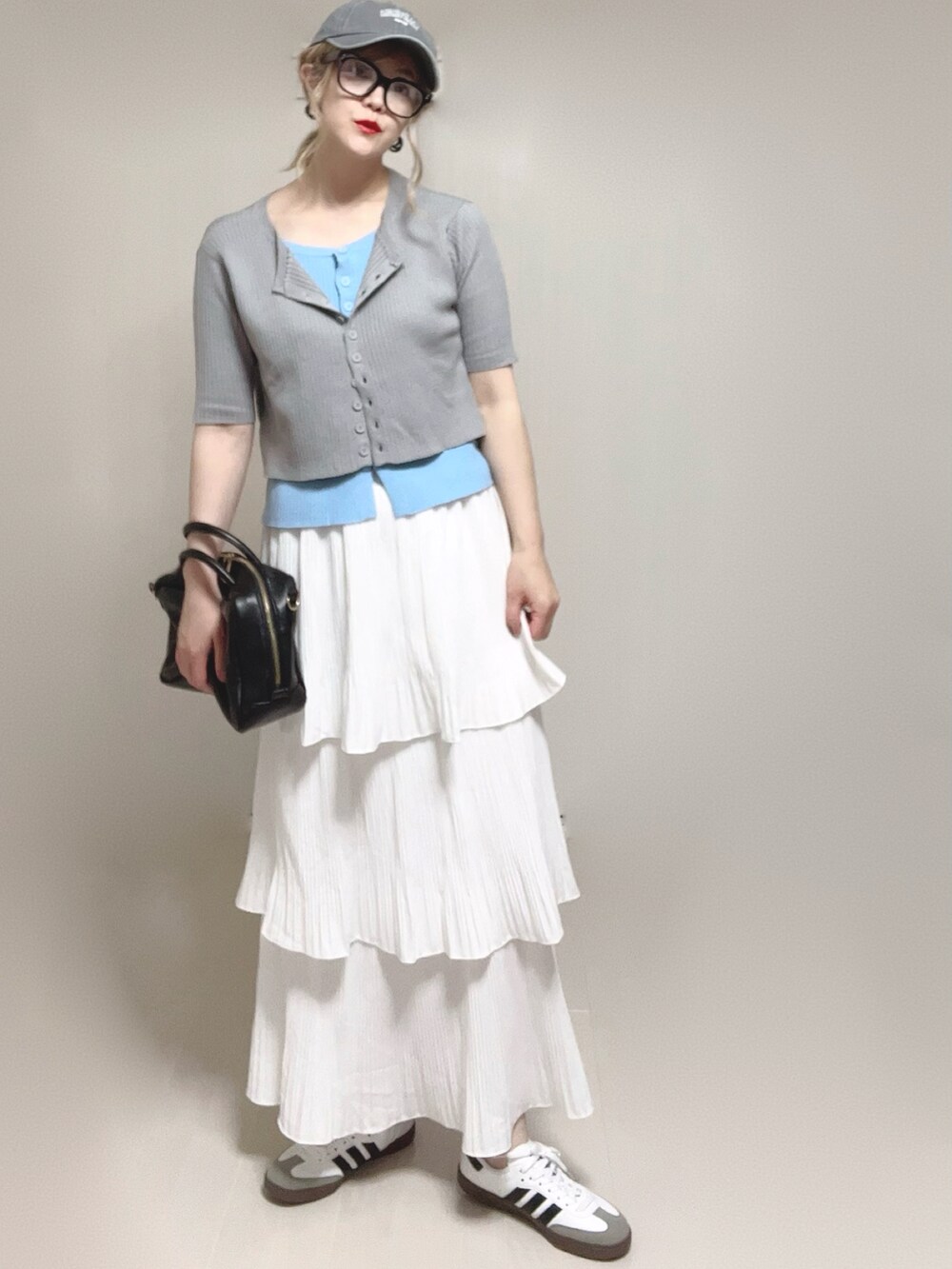 グレー系のニット/セーター、ブラック系のボストンバッグ、ホワイト系のスカートを着用したレディースの夏コーディネートの3枚目の写真