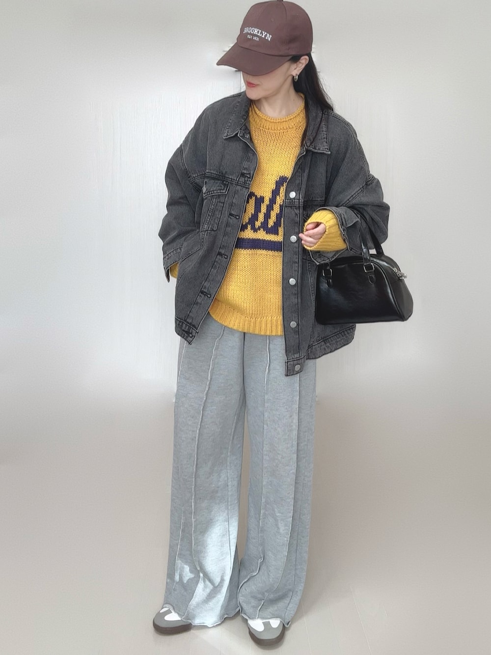 イエロー系のニット/セーター、ブラック系のデニムジャケット、グレー系のスウェットパンツを着用したレディースの冬コーディネートの4枚目の写真