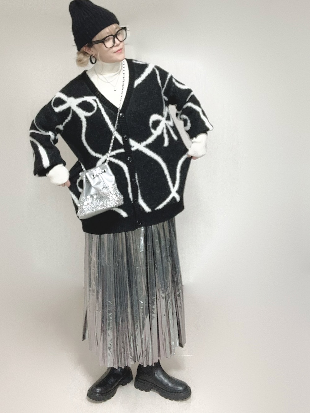 ブラック系のカーディガン/ボレロ、ホワイト系のニット/セーター、ブラック系のブーツを着用したレディースの冬コーディネートの2枚目の写真