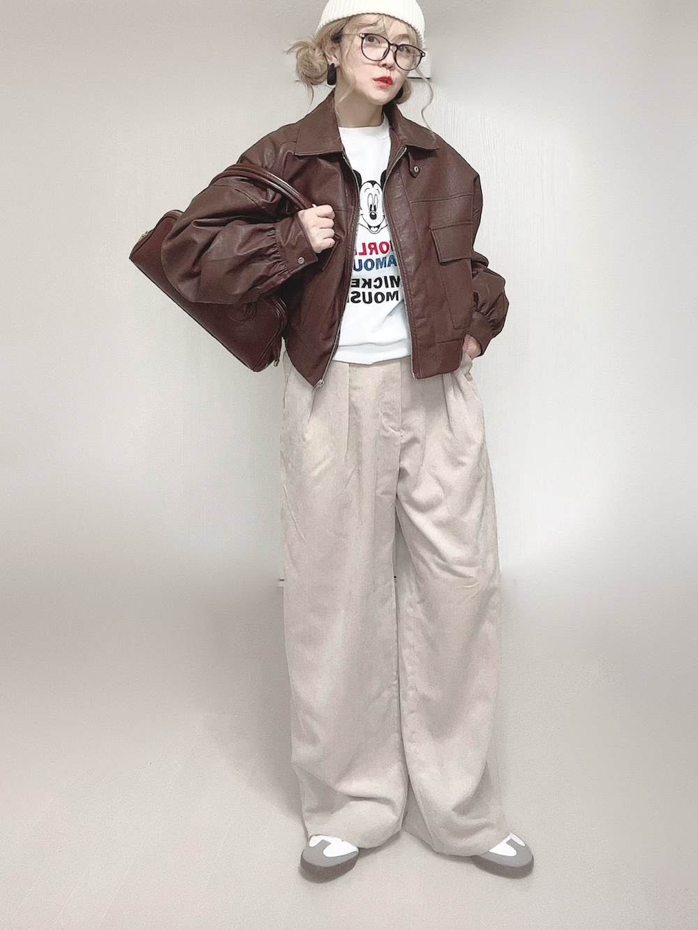 ブラウン系のブルゾン、ブラウン系のショルダーバッグ、ベージュ系のスラックスを着用したレディースの冬コーディネートの3枚目の写真