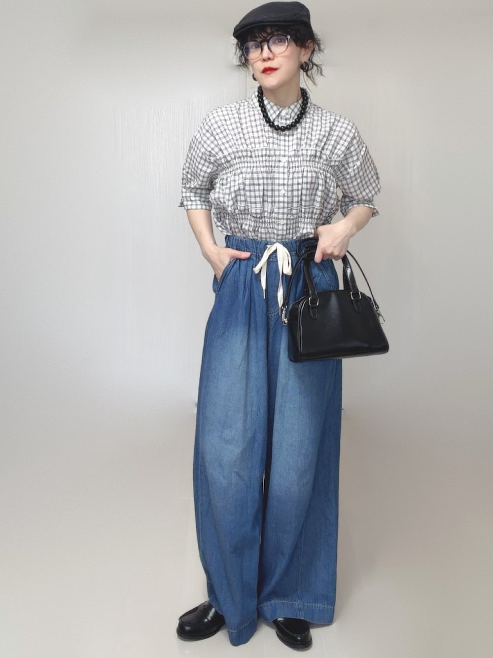 ブラック系のボストンバッグ、ホワイト系のシャツ/ブラウス、ブルー系のデニムパンツを着用したレディースの春コーディネートの5枚目の写真