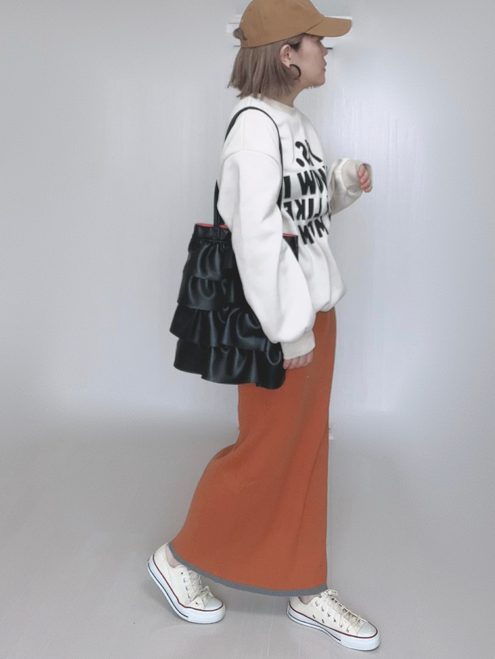 オレンジ系のスカート、ホワイト系のスニーカーを着用したレディースの冬コーディネートの4枚目の写真