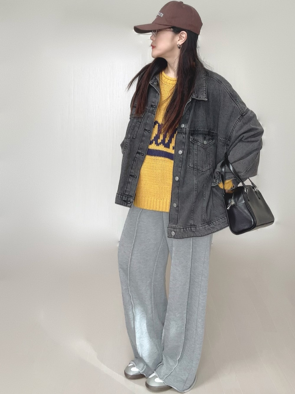 イエロー系のニット/セーター、ブラック系のデニムジャケット、グレー系のスウェットパンツを着用したレディースの冬コーディネートの5枚目の写真