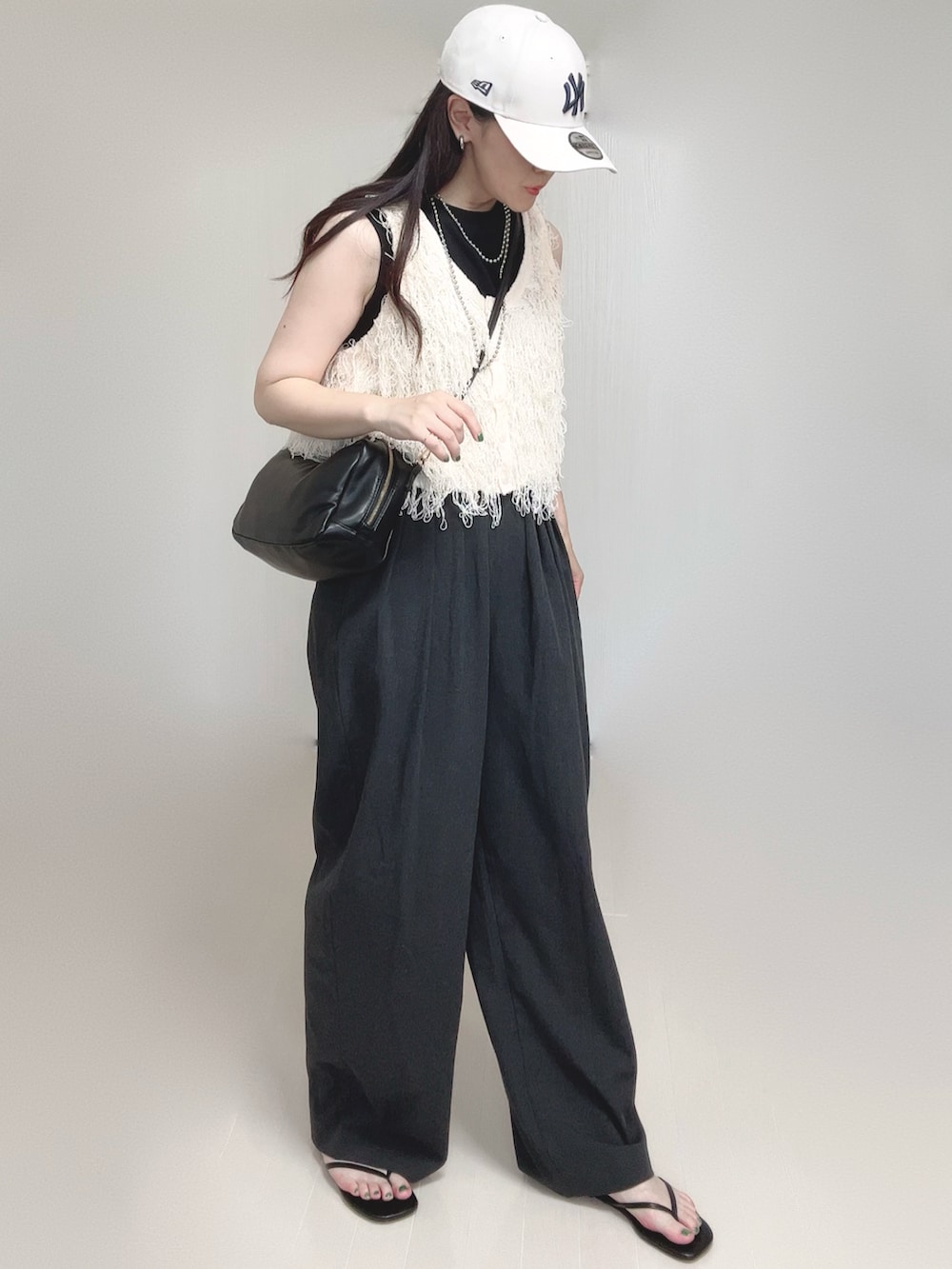 ホワイト系のベスト、グレー系のスラックス、ブラック系のボストンバッグを着用したレディースの夏コーディネートの3枚目の写真