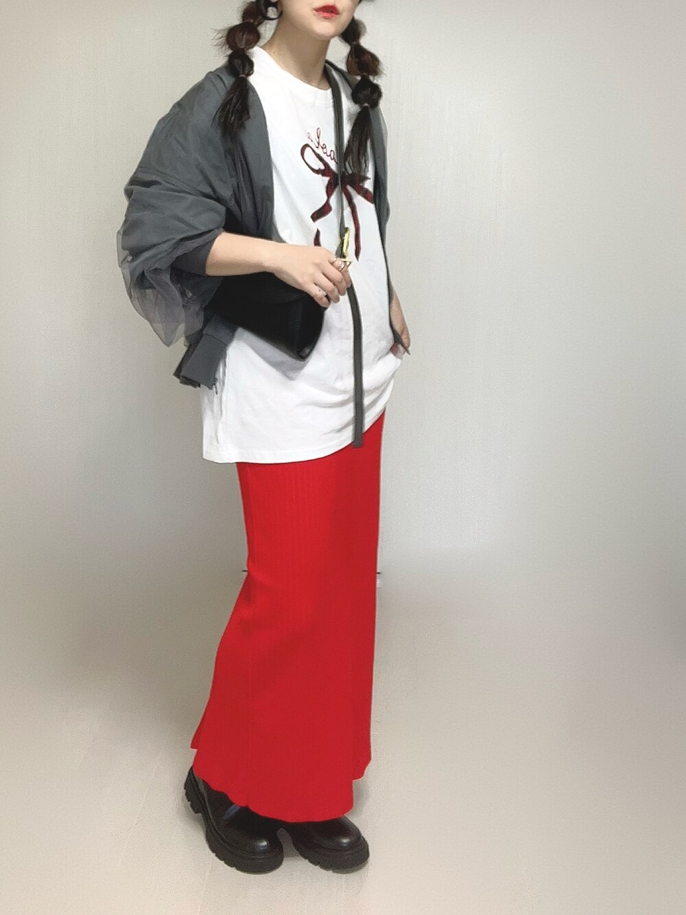 ブラック系のブーツ、ホワイト系のTシャツ/カットソー、レッド系のスカートを着用したレディースの秋コーディネートの4枚目の写真