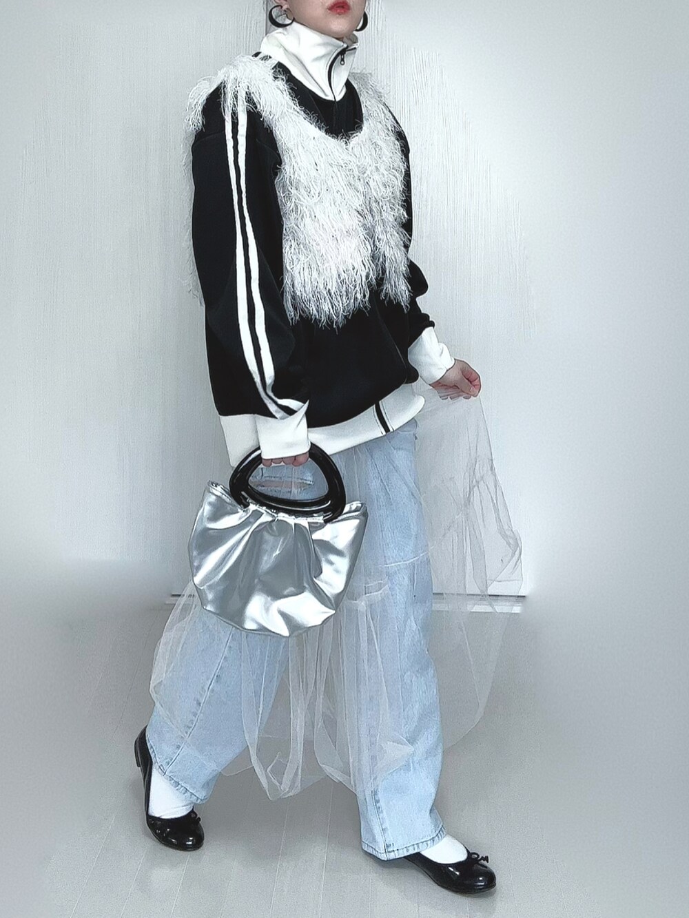 ブラック系のブルゾン、ホワイト系のベスト、ホワイト系のスカートを着用したレディースの春コーディネートの3枚目の写真