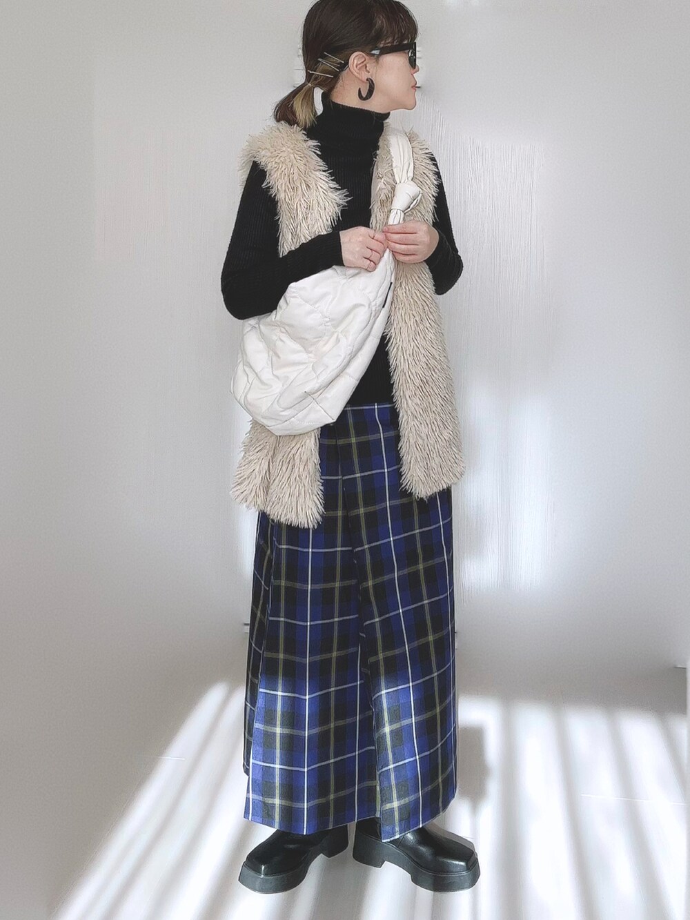 ホワイト系のベスト、ホワイト系のショルダーバッグ、ブラック系のブーツを着用したレディースの冬コーディネートの3枚目の写真