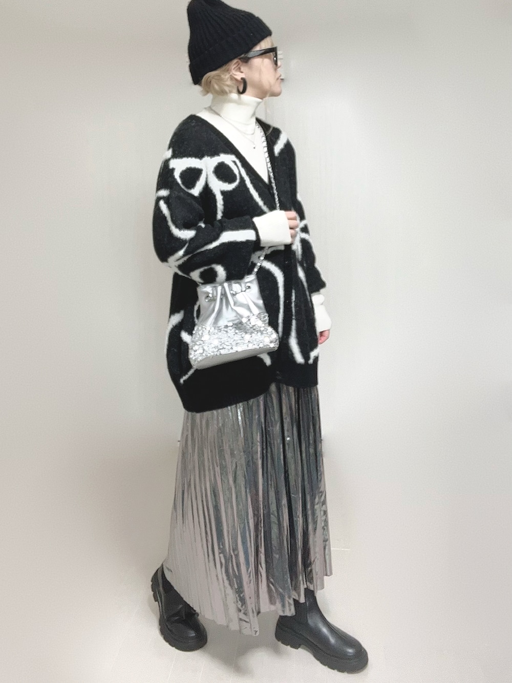 ブラック系のカーディガン/ボレロ、ホワイト系のニット/セーター、ブラック系のブーツを着用したレディースの冬コーディネートの3枚目の写真