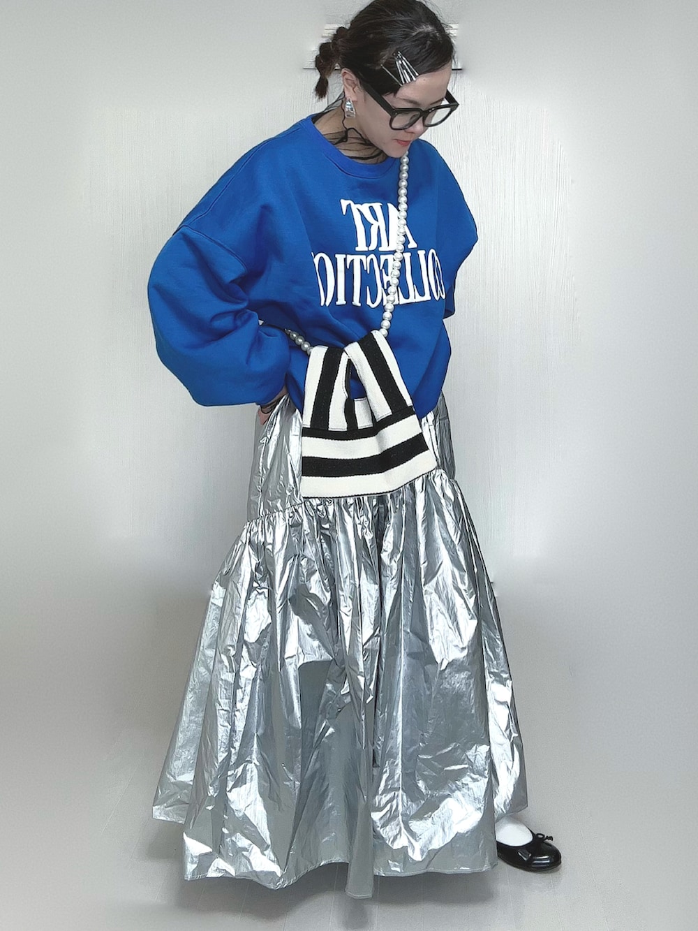 シルバー系のスカート、ブラック系のTシャツ/カットソー、ホワイト系のショルダーバッグを着用したレディースの春コーディネートの4枚目の写真