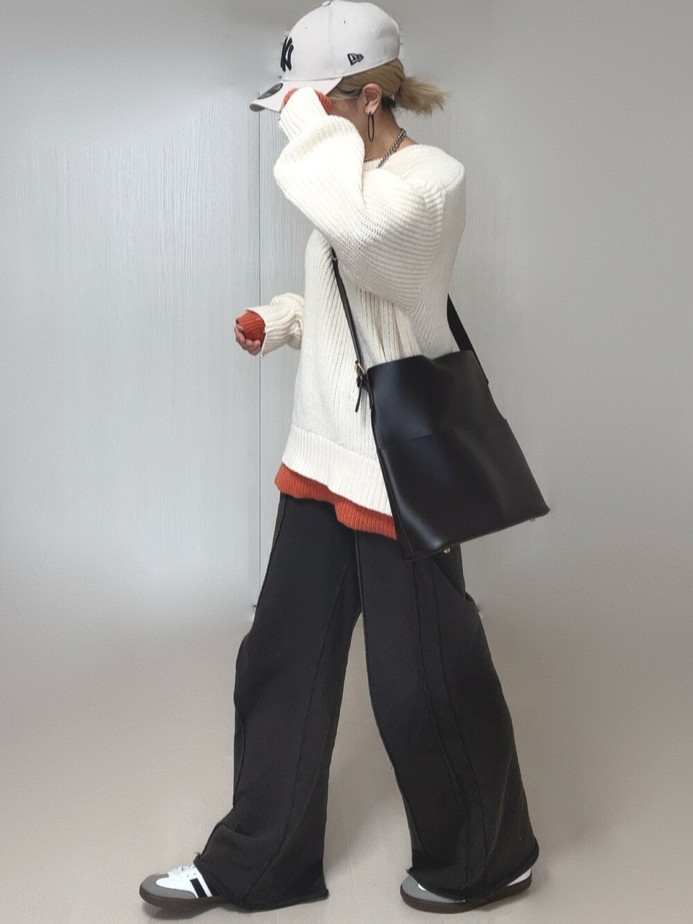 ブラック系のスウェットパンツ、ホワイト系のニット/セーター、ホワイト系のキャップを着用したレディースの冬コーディネートの2枚目の写真
