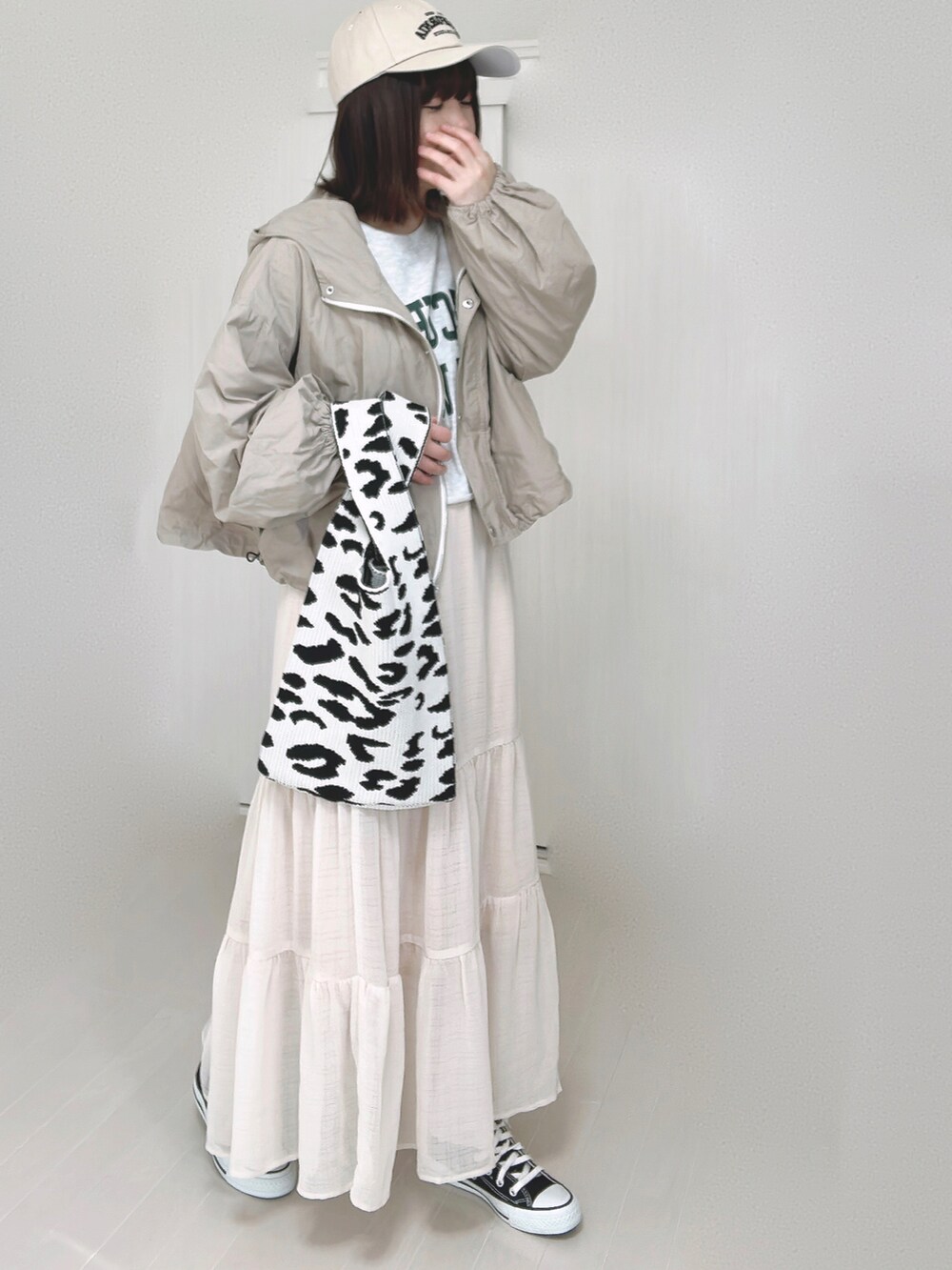 ベージュ系のマウンテンパーカー、ホワイト系のスカート、ブラック系のスニーカーを着用したレディースの春コーディネートの3枚目の写真