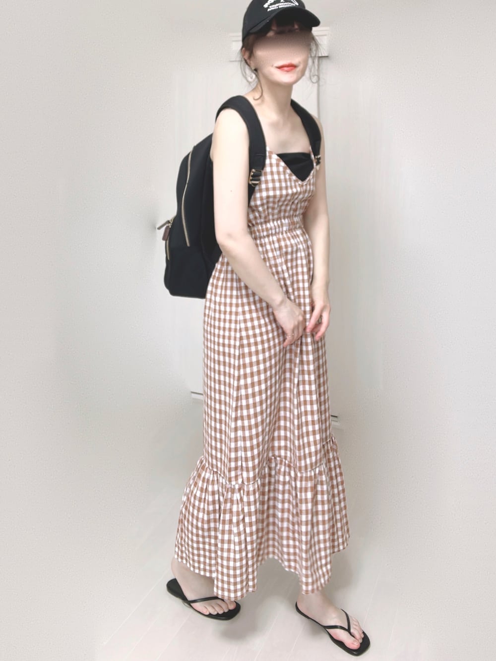 ブラック系のバックパック/リュック、オレンジ系のワンピース、ブラック系のサンダルを着用したレディースの夏コーディネートの2枚目の写真